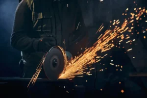 Profissional cortando metal na indústria metalúrgica, exemplificando estratégias de redução de desperdícios e aumento da eficiência produtiva na metalurgia.