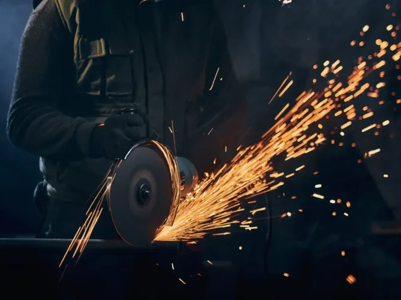 Profissional cortando metal na indústria metalúrgica, exemplificando estratégias de redução de desperdícios e aumento da eficiência produtiva na metalurgia.